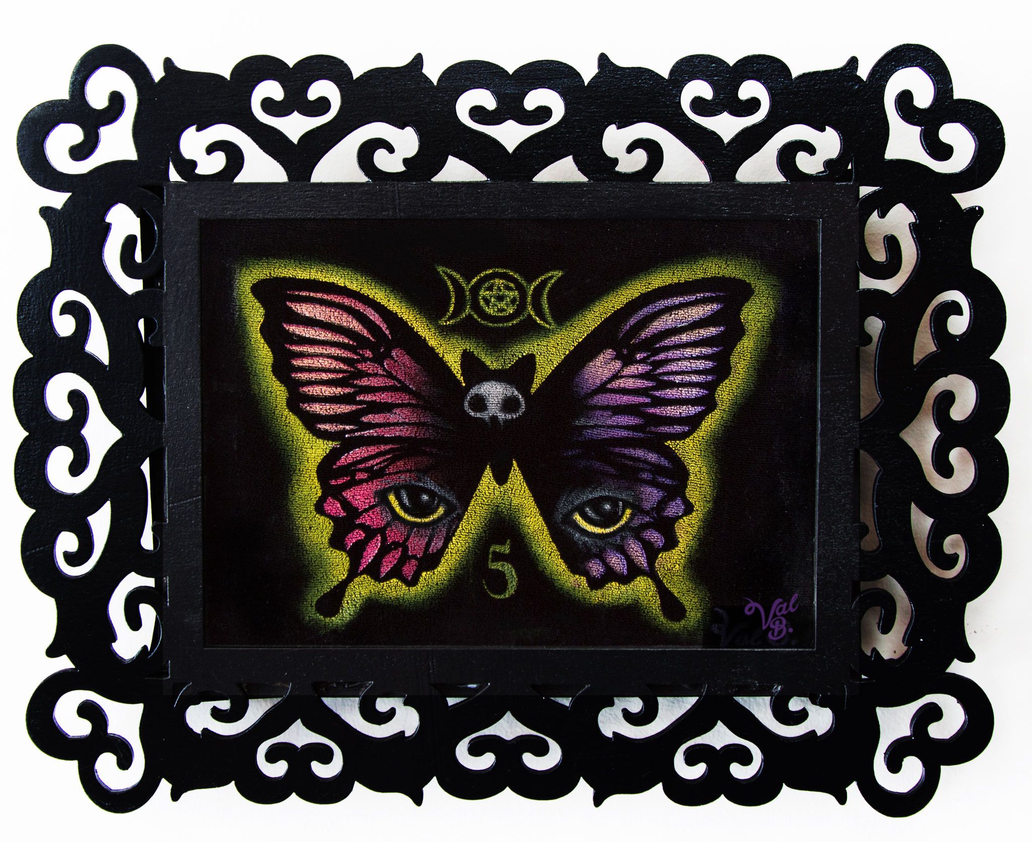 Catterfly On Velvet. A butterfly with pink and purple wings, a cat's eye on each lower wing and a skull-faced cat head for a body, with a triple moon pentacle above and the number 5 below, in a yellow-green glow. Painted on black velvet in an ornate black filigree frame.
