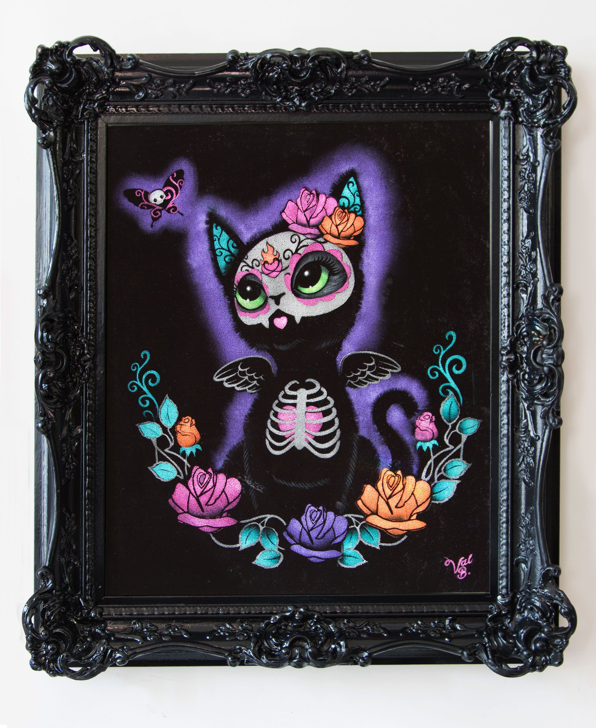Kitty Rose On Velvet. A winged black kitten with a sugar skull face, big green eyes and a ribcage with a pink heart wears pink and orange roses and sits in a wreath of roses under a skull-faced moth, in a purple glow. Painted on black velvet in an ornate black baroque frame.